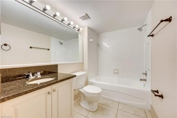a bathroom with a granite countertop bathtub sink vanity mirror and toilet