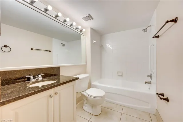 a bathroom with a granite countertop bathtub sink vanity mirror and toilet