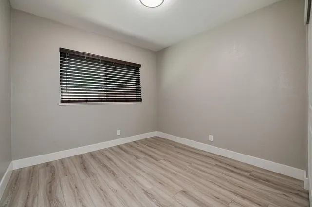 an empty room with wooden floor fireplace and windows