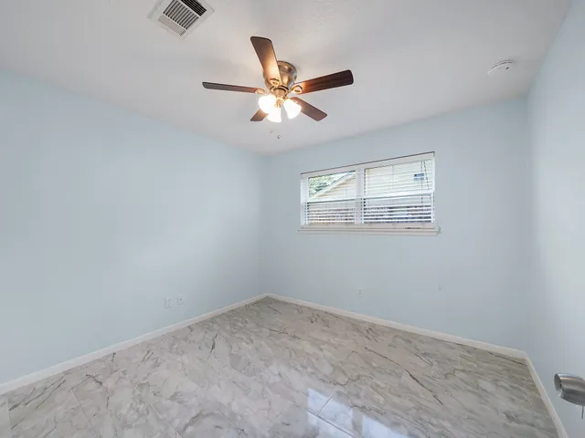 an empty room with a window and a fan