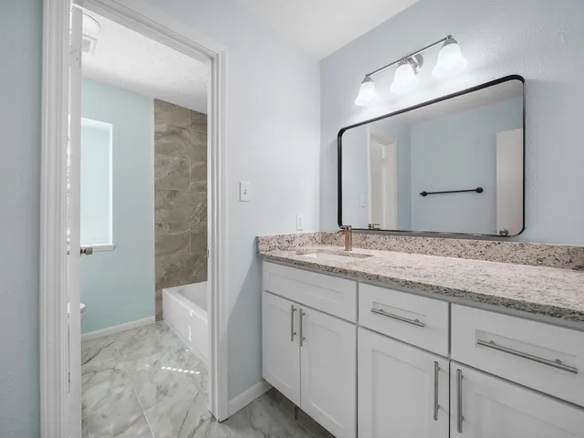 a bathroom with a granite countertop sink and a mirror