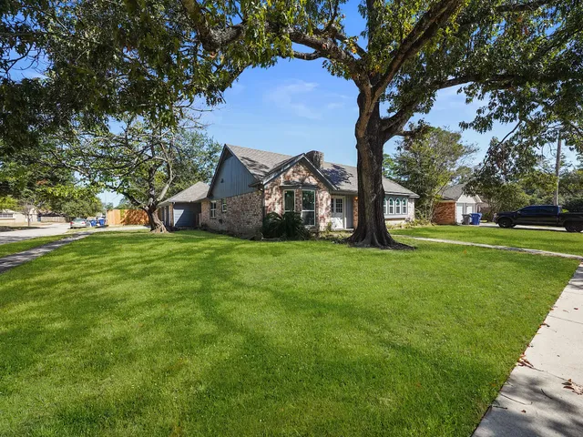 a view of a tree in front of a house with a garden