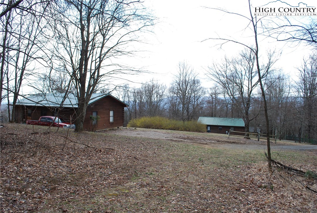 238 Misty Ridge Road Millers Creek, NC 28651 - Photo 1 of 22 a view of a backyard with large trees and wooden fence