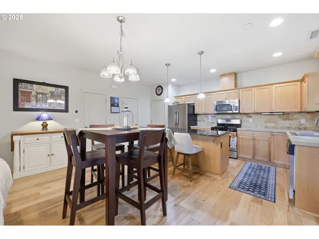 a open dining room with stainless steel appliances kitchen island granite countertop a dining table chairs and a refrigerator