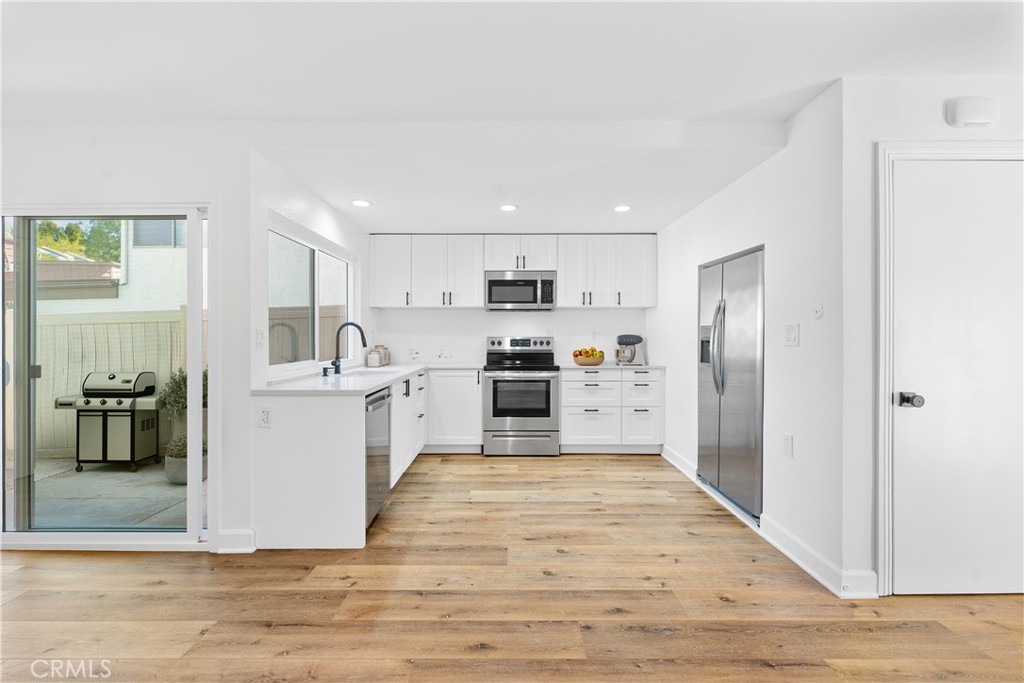 10179 Larwin Avenue, Unit 5 Chatsworth, CA 91311 - Photo 7 of 53 a kitchen with white cabinets and stainless steel appliances