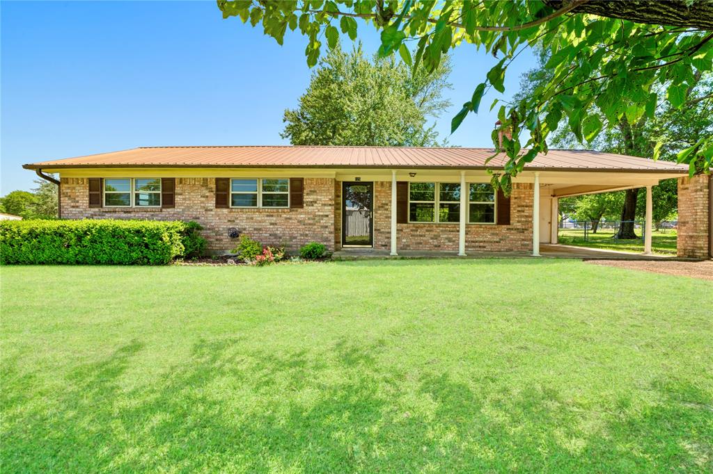 125 Harrison Detroit, TX 75436 - Photo 1 of 1 Single story home featuring a front lawn, an attached carport, brick siding, and metal roof