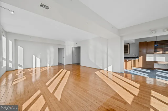 a view of an empty room with wooden floor and a window