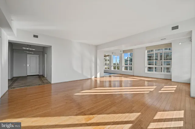 a view of an empty room with window and wooden floor