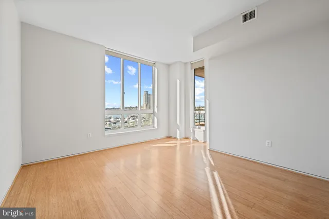 an empty room with wooden floor and windows