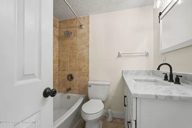 a bathroom with a granite countertop sink a toilet and shower