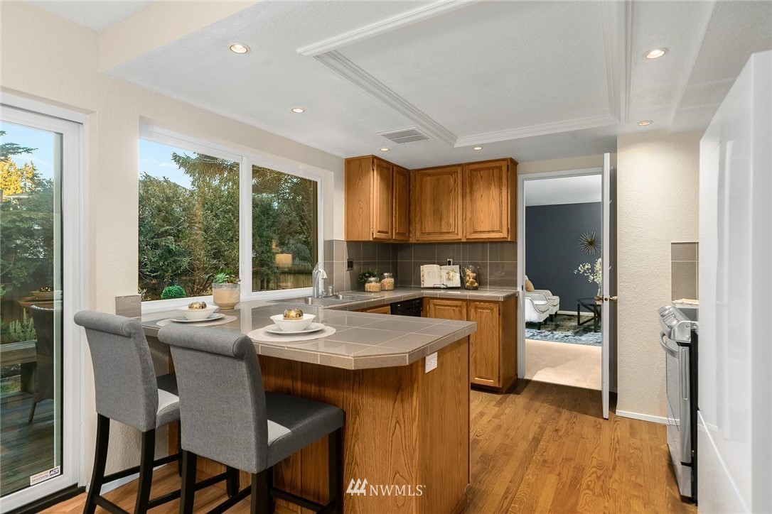 707 Harvest Road Bothell, WA 98012 - Photo 8 of 27 a kitchen with a stove a refrigerator and a dining table with wooden floor