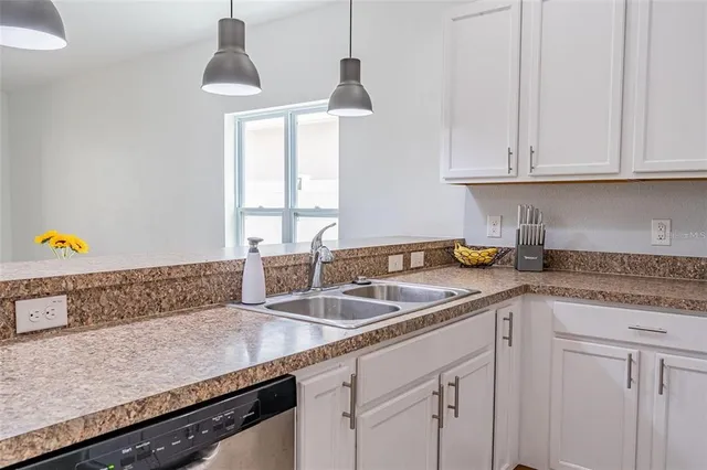 a kitchen with granite countertop a sink a stove and cabinets
