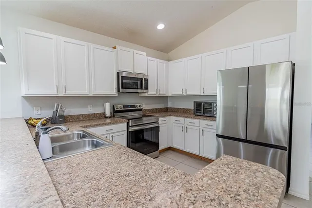 a kitchen with granite countertop a refrigerator stove top oven and sink