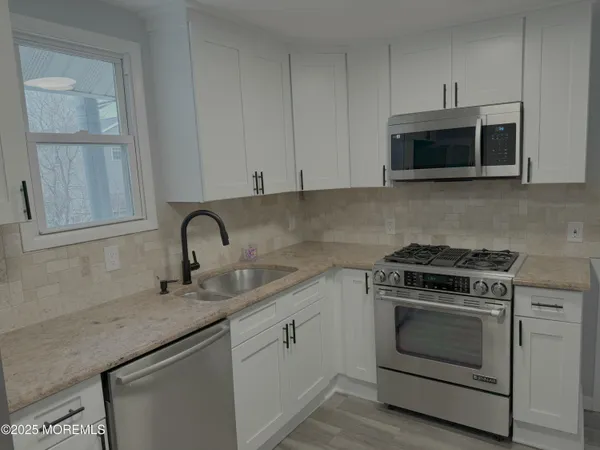 a kitchen with granite countertop white cabinets and stainless steel appliances