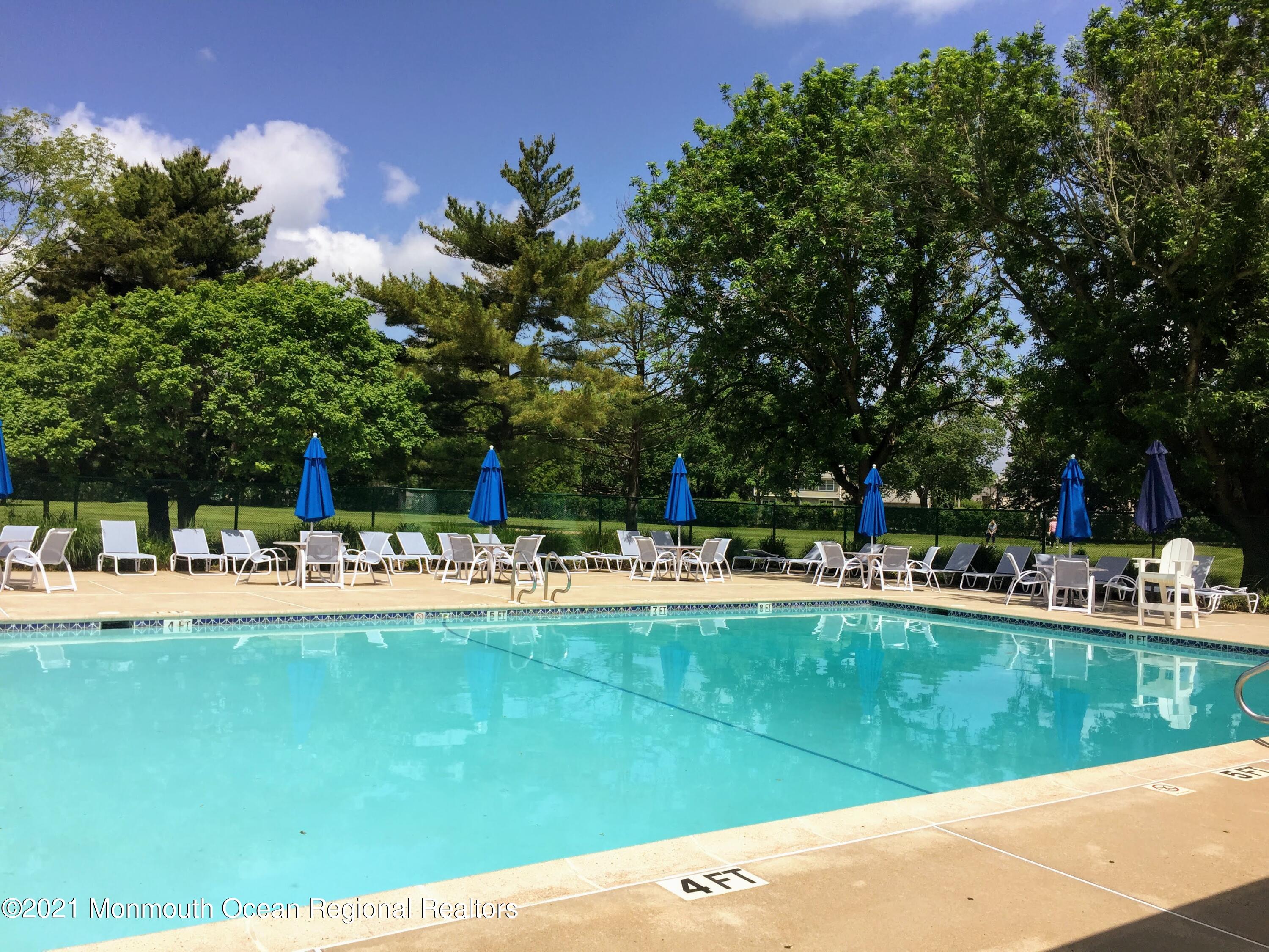 121 Walnut Drive Spring Lake Heights, NJ 07762 - Photo 38 of 44 a view of a swimming pool with a bench and trees in the background