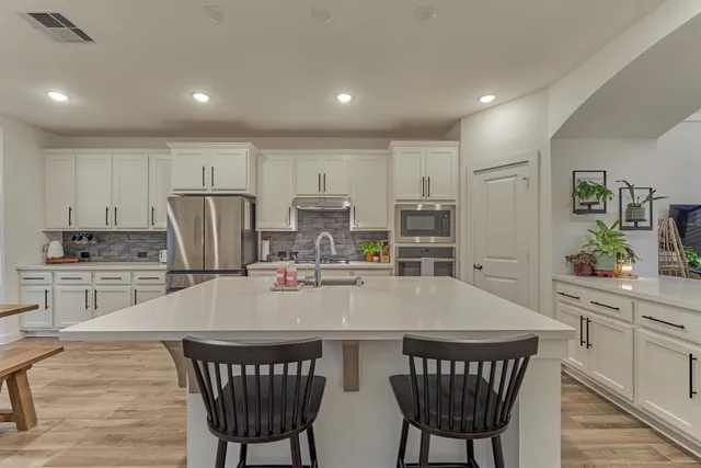a kitchen with stainless steel appliances a table chairs and a refrigerator