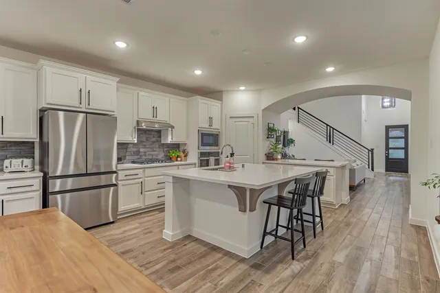 a kitchen with stainless steel appliances a refrigerator a stove a sink dishwasher and a refrigerator with wooden floor