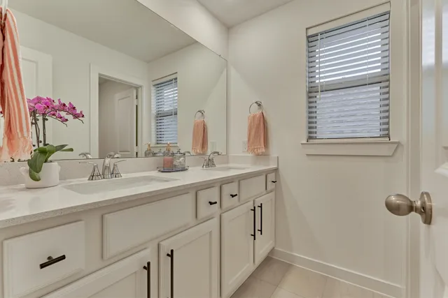 a bathroom with double vanity sink a window and a mirror