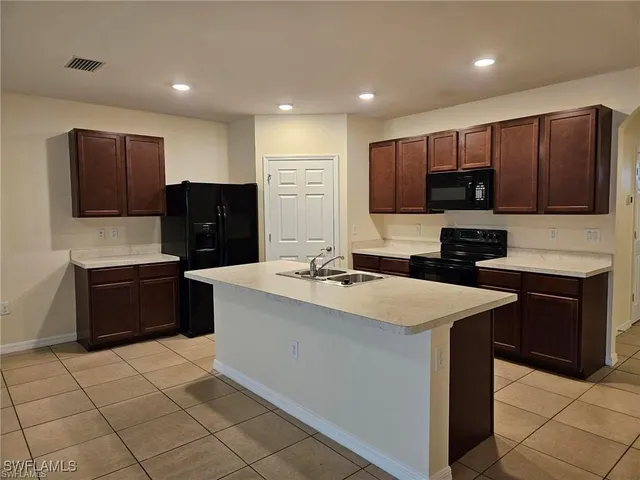 a view of kitchen with stainless steel appliances kitchen island granite countertop a refrigerator sink and cabinets