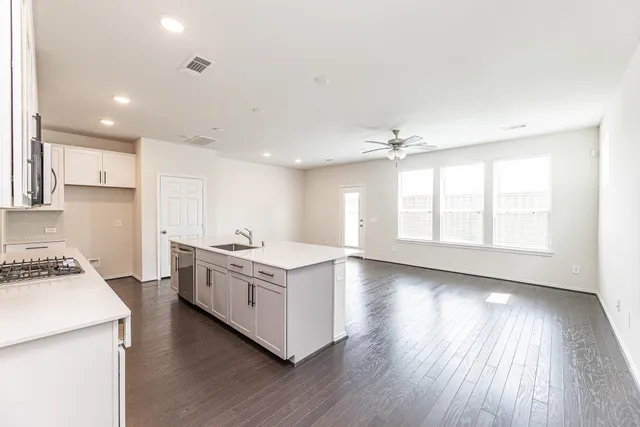 a kitchen with a stove a sink and wooden floor
