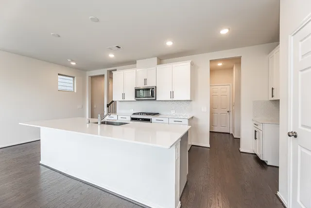 a kitchen with a sink a stove a refrigerator and white cabinets with wooden floor