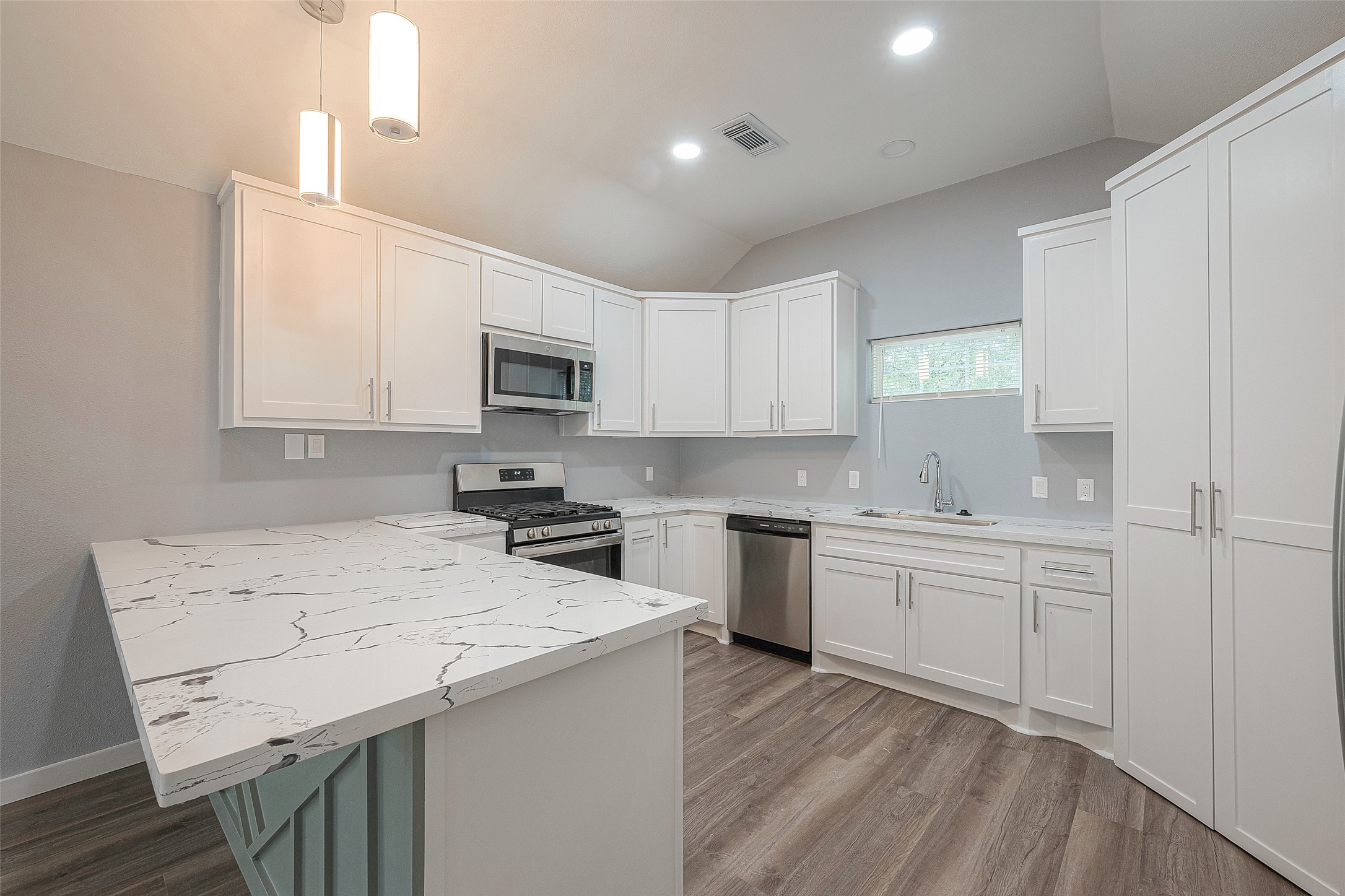 2725 Avenue F, Unit RR Rosenberg, TX 77471 - Photo 11 of 23 a kitchen with a sink a stove a microwave a center island and cabinets
