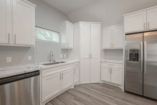 a kitchen with a sink cabinets stainless steel appliances and a window