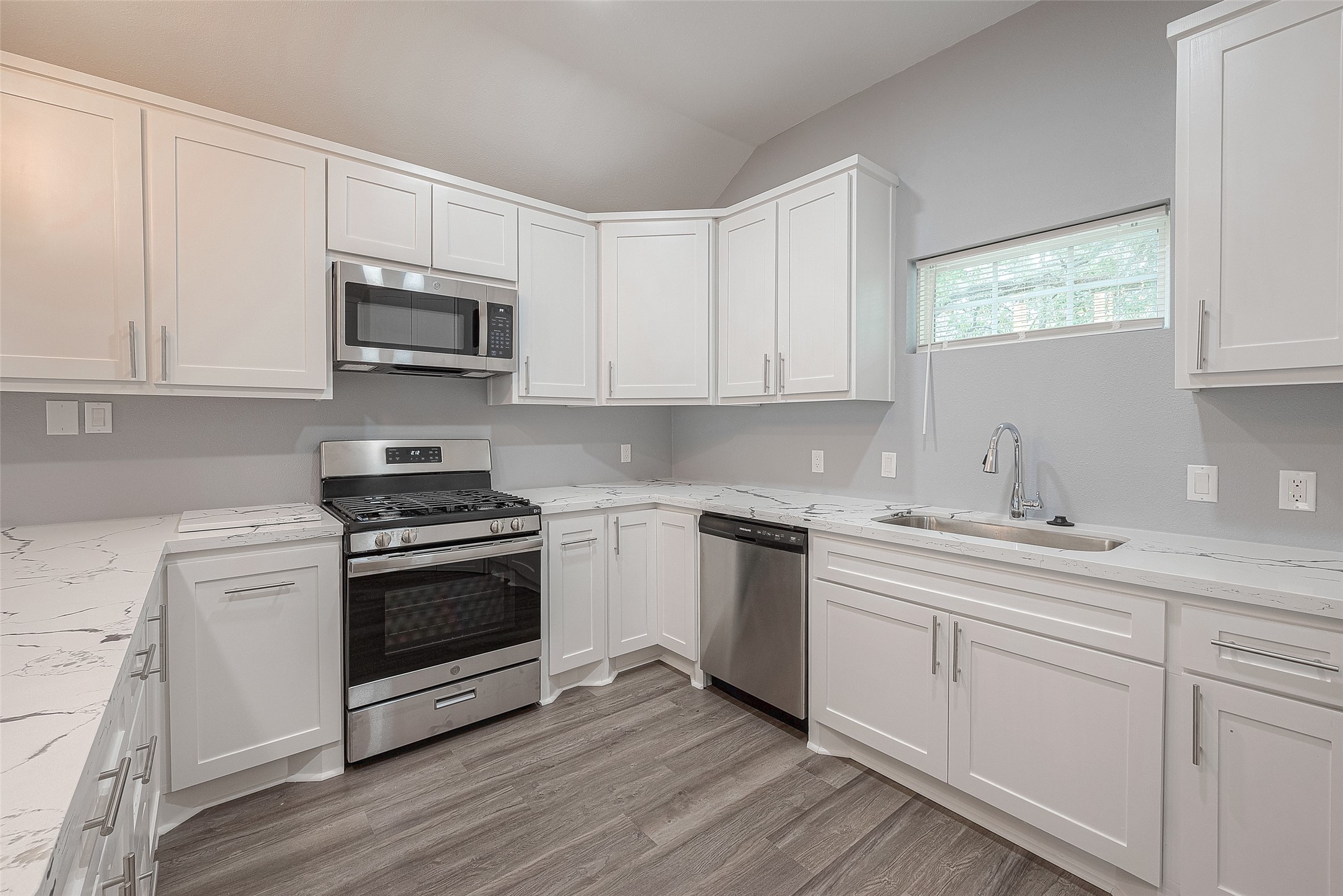 2725 Avenue F, Unit RR Rosenberg, TX 77471 - Photo 12 of 23 a kitchen with stainless steel appliances granite countertop a sink dishwasher a stove and a microwave oven with cabinets