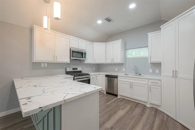 a kitchen with a sink a stove a microwave a center island and cabinets