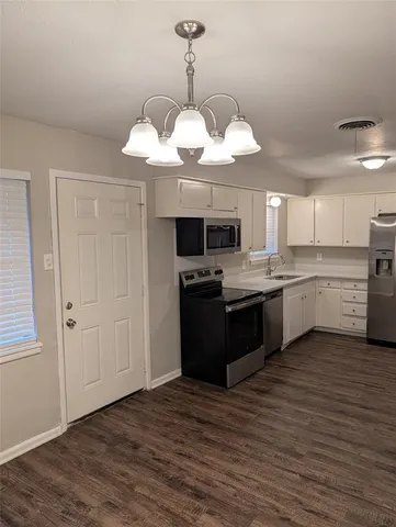 a kitchen with stainless steel appliances granite countertop a refrigerator a sink dishwasher a stove and white cabinets with wooden floor