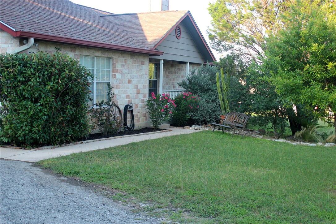 a view of a house with brick walls and a yard with plants