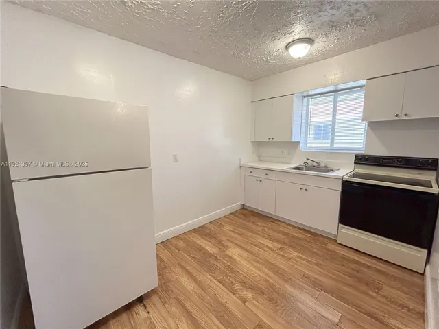 a kitchen with a refrigerator and a stove top oven