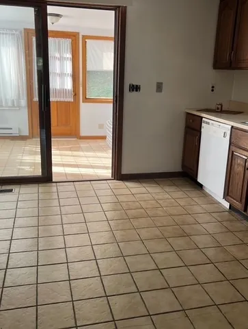 a view of a refrigerator in kitchen and an empty room