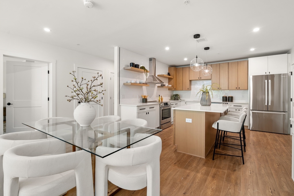 20 Audubon Way, Unit 408 Canton, MA 02021 - Photo 5 of 22 a kitchen with stainless steel appliances granite countertop a dining table chairs refrigerator and cabinets