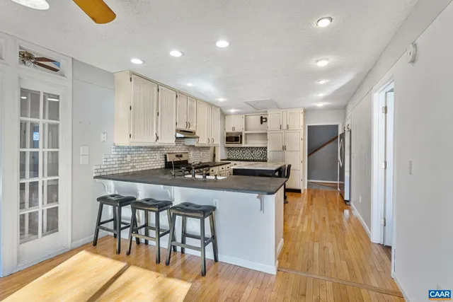 a kitchen with stainless steel appliances granite countertop a table chairs sink refrigerator and cabinets