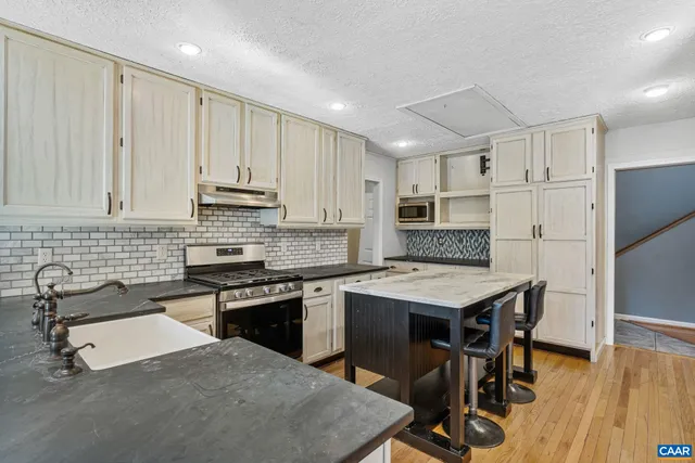 a kitchen with stainless steel appliances granite countertop a table chairs sink refrigerator and cabinets