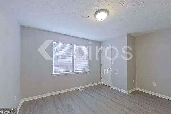 an empty room with wooden floor fan and windows