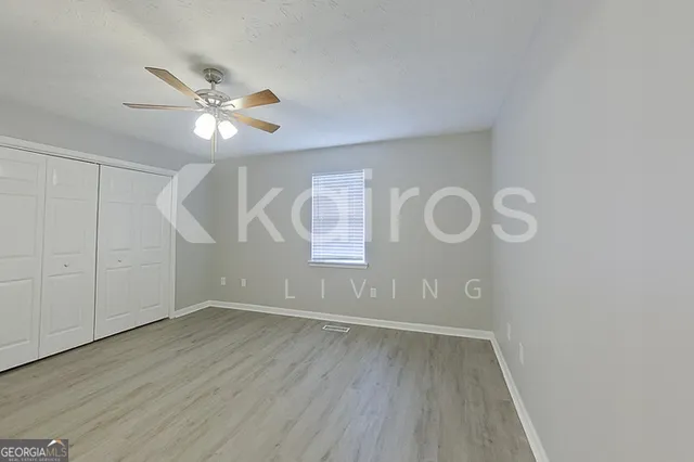 an empty room with wooden floor fan and windows