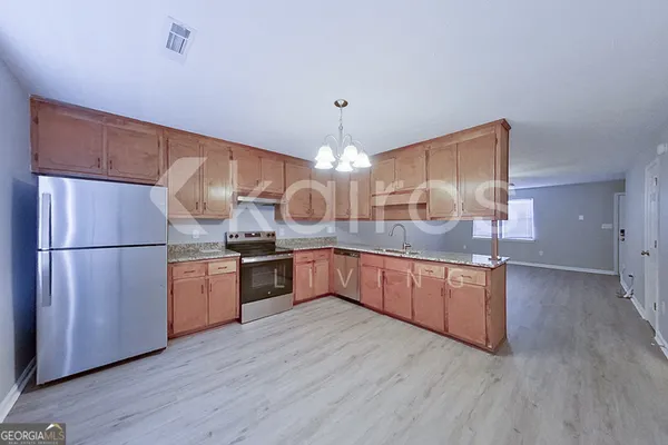 a kitchen with stainless steel appliances granite countertop a refrigerator a sink dishwasher a oven and a dining table with wooden floor