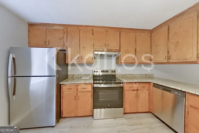 a kitchen with stainless steel appliances granite countertop a refrigerator and a stove top oven