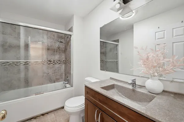 a bathroom with a granite countertop sink a toilet a mirror and shower