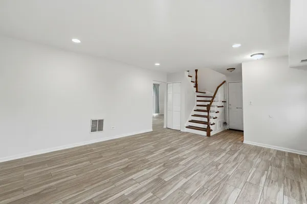 a view of an empty room with stairs and a ceiling fan