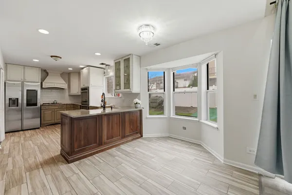 a large kitchen with stainless steel appliances a large counter top a stove and a wooden floors