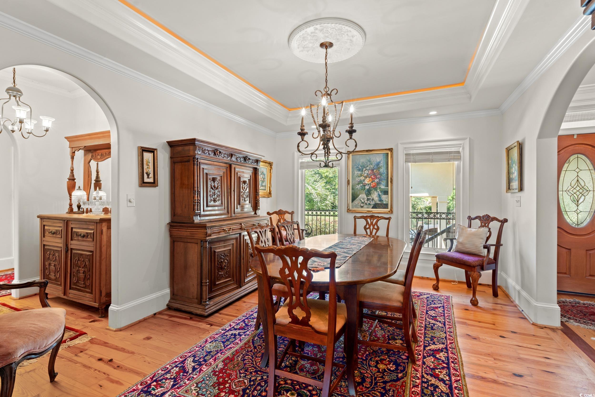 2790 Fowler Road Loris, SC 29569 - Photo 11 of 40 Dining space with arched walkways, a chandelier, a tray ceiling, ornamental molding, and light wood-style floors