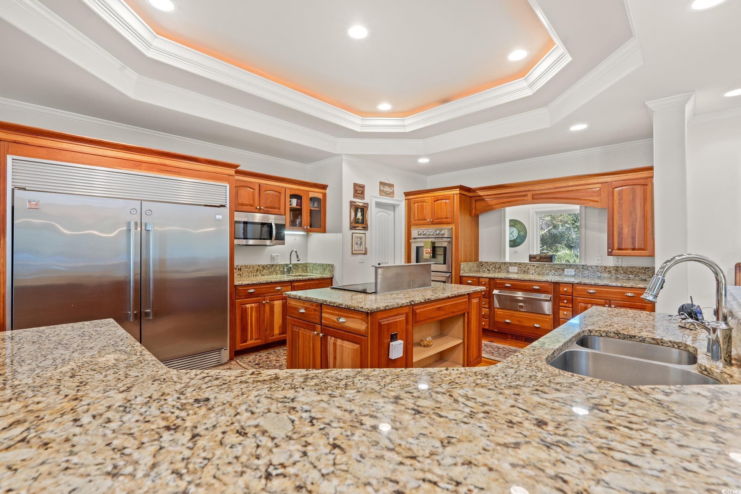 2790 Fowler Road Loris, SC 29569 - Photo 18 of 40 Kitchen with a tray ceiling, a kitchen island, light stone countertops, glass insert cabinets, and stainless steel appliances
