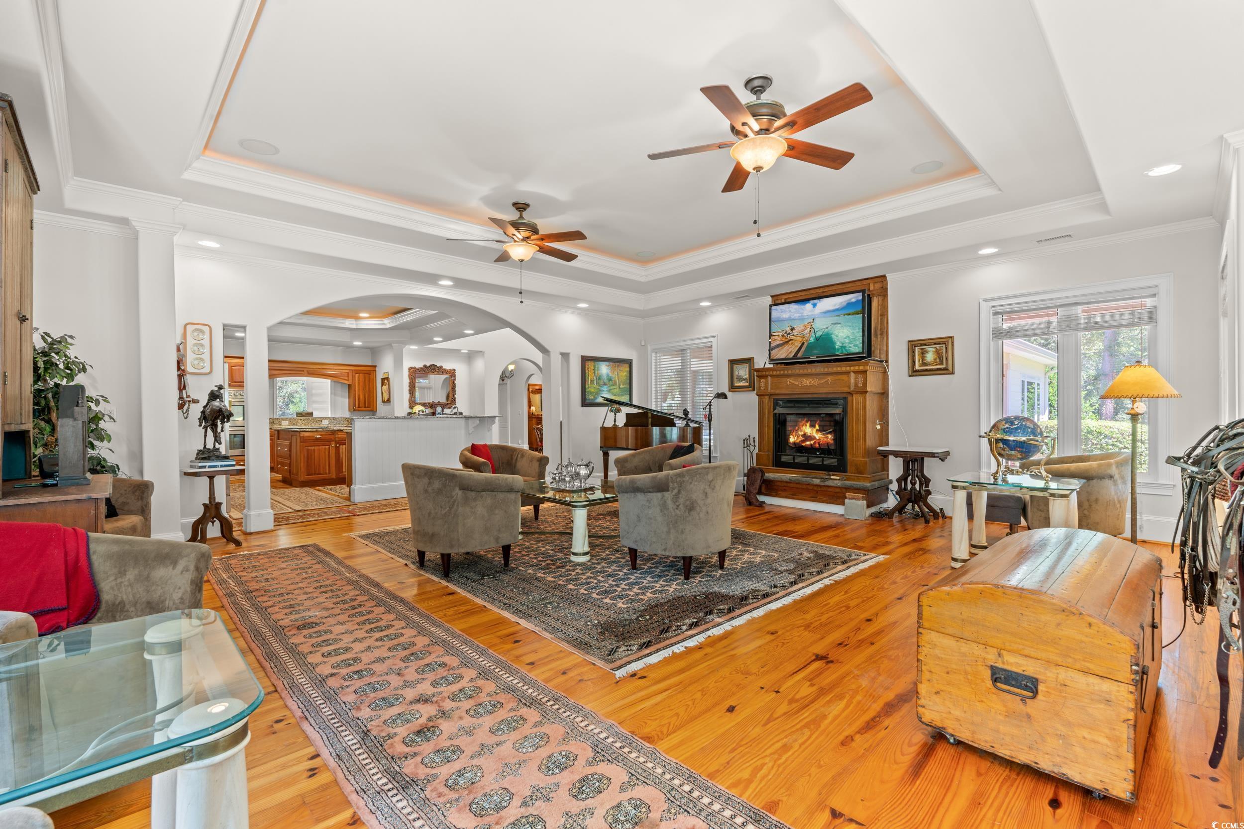 2790 Fowler Road Loris, SC 29569 - Photo 20 of 40 Living room with a tray ceiling, ornamental molding, ceiling fan, light wood-style floors, and a warm lit fireplace