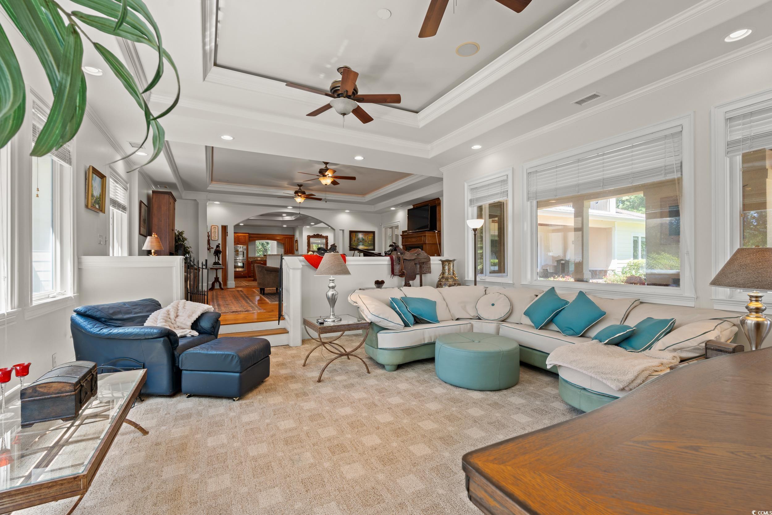 2790 Fowler Road Loris, SC 29569 - Photo 21 of 40 Living room with a tray ceiling, ceiling fan, crown molding, arched walkways, and light carpet
