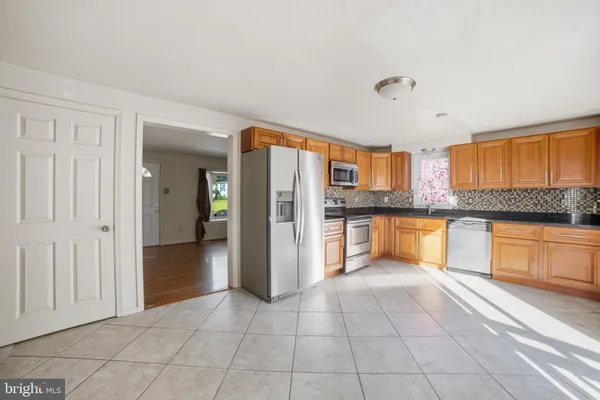 a large kitchen with granite countertop a refrigerator and a stove top oven