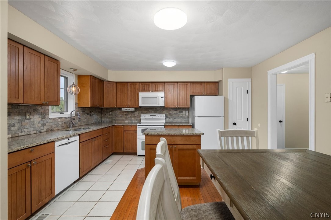 1322 Sawmill Road Sangerfield, NY 13480 - Photo 21 of 50 Warm wood cabinetry and granite countertops ground this functional kitchen with dual flooring textures.