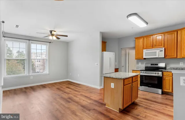 a kitchen with stainless steel appliances granite countertop a stove a sink dishwasher and a refrigerator with wooden floor